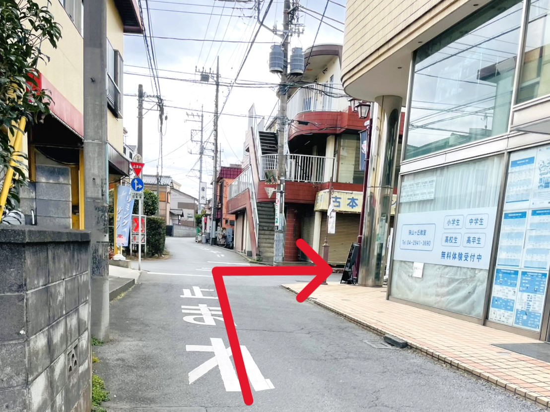 古本屋「中山書店」や「城南コベッツ 狭山ヶ丘教室」の看板が見えます。「中山書店」のところを右に曲がります