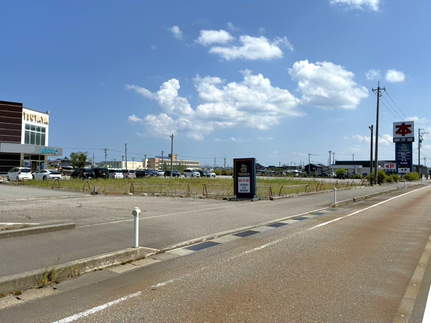 「明文堂書店 高岡射水店」駐車場への入口です。国道8号線坂東高架下の側道からお越しの際は、左折してお入りいただけます。