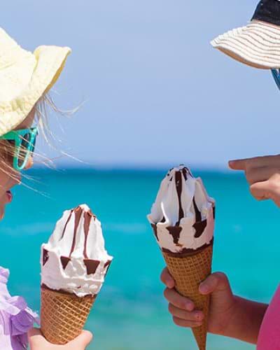 Two young girls eating ice cream on a beach in Italy