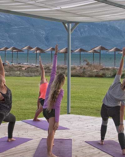 group of people doing yoga by the sea