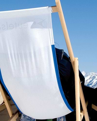 people relaxing on deck chairs soaking up the sun on a ski holiday