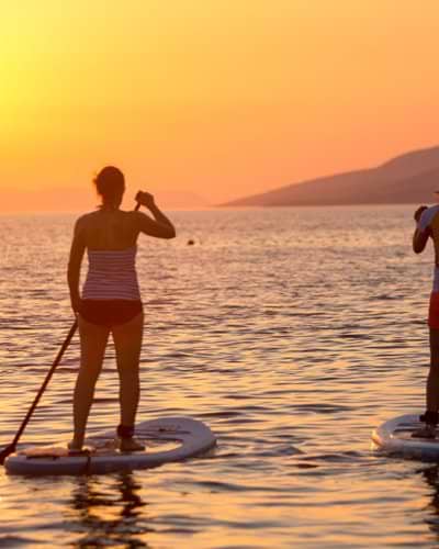 People paddle boarding at sunset