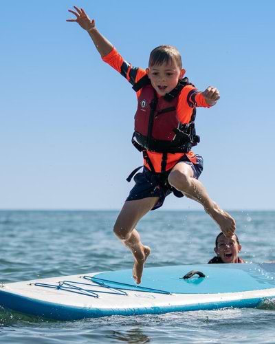 boy jumping from a paddle board