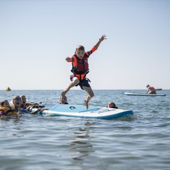 boy jumping from paddle  board