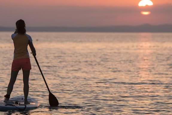 2 people stand up paddle boarding at sunset