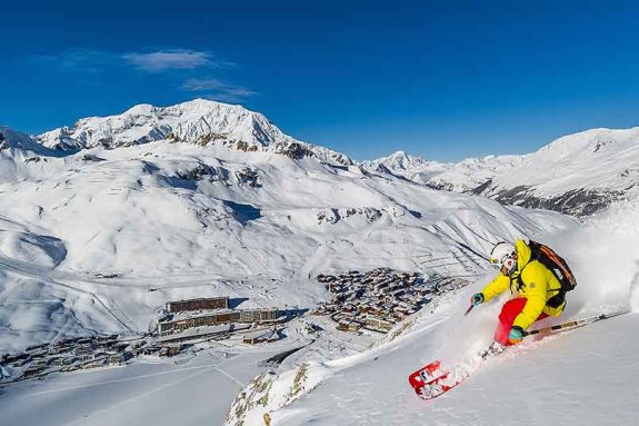 Person Skiing high above village in valley below 
