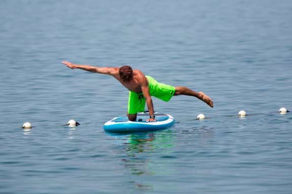 Man doing yoga on stand up paddle board