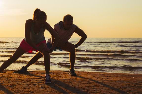 two people exercising at the beach