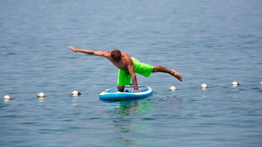 Man doing yoga on stand up paddle board