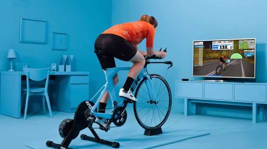 Man in living room and a static bike joining a Zwift ride