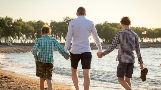 Father and sons walking on a beach