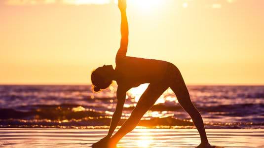 woman practising yoga on a beach