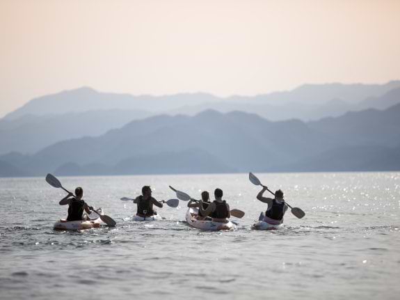 A group of kayakers in front of distant mountains