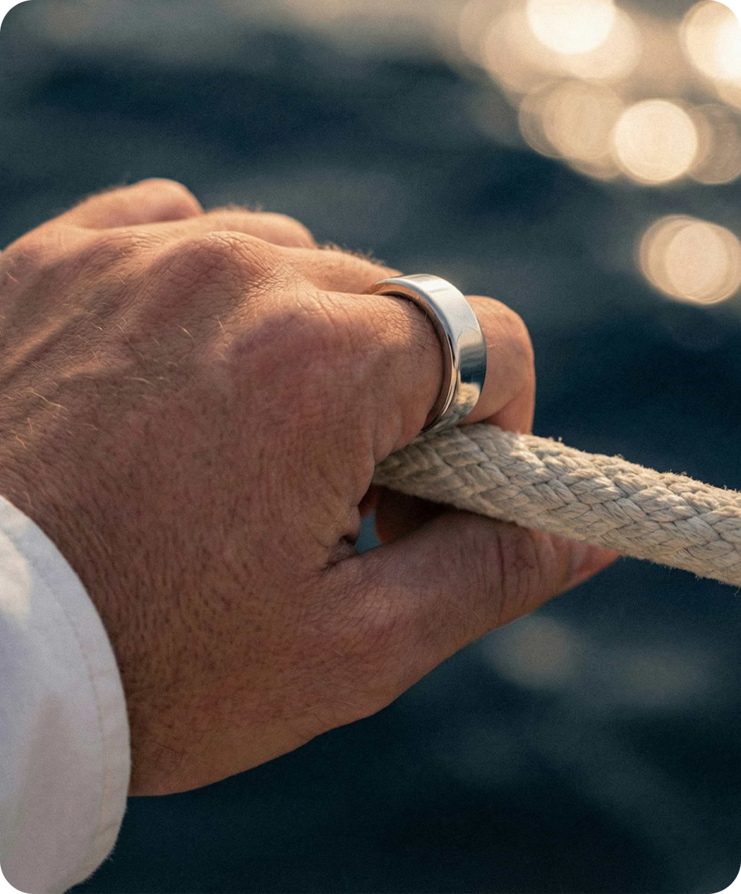A hand wearing the Ultrahuman Ring AIR holding a rope