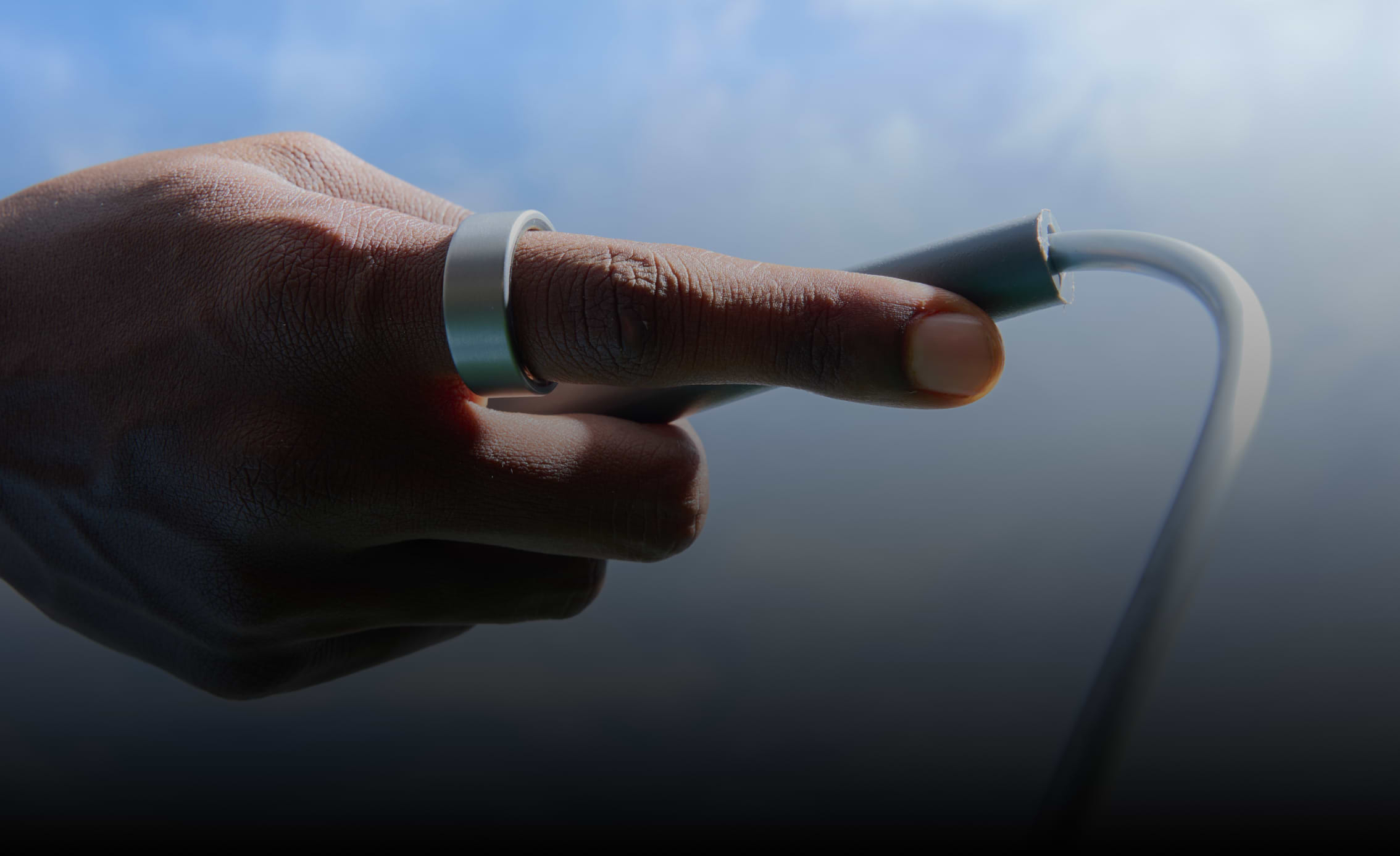 Ultrahuman Home device on dark surface with blurred background of person wearing ring