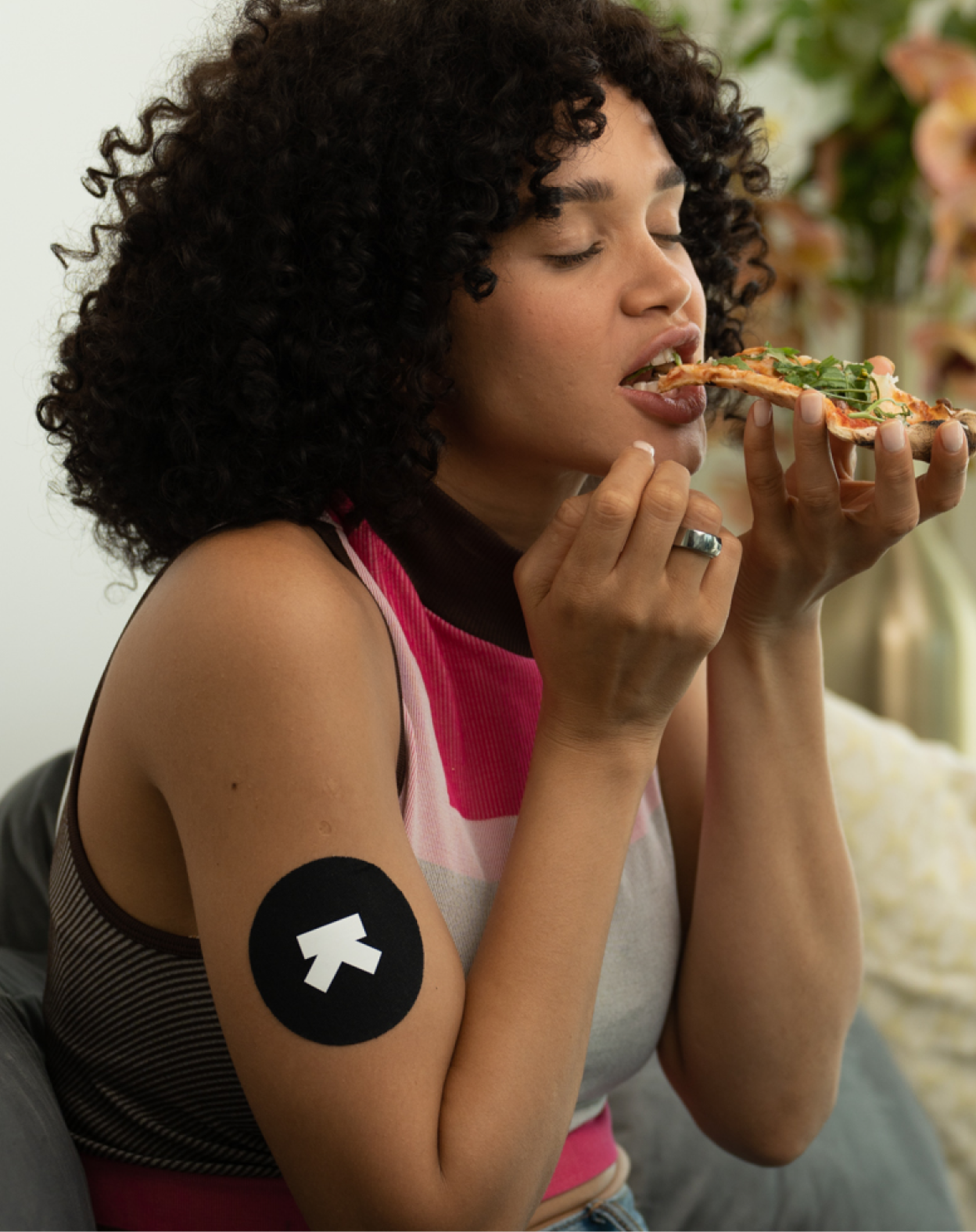 woman eating pizza with M1 applied to arm