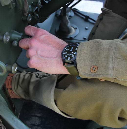 WW2 Battlefield mit GI in einem automobil, Uhr in Aiguille, in den Farben Dunkelolivgrün, Hellmauve und Hellgrau-Blau.