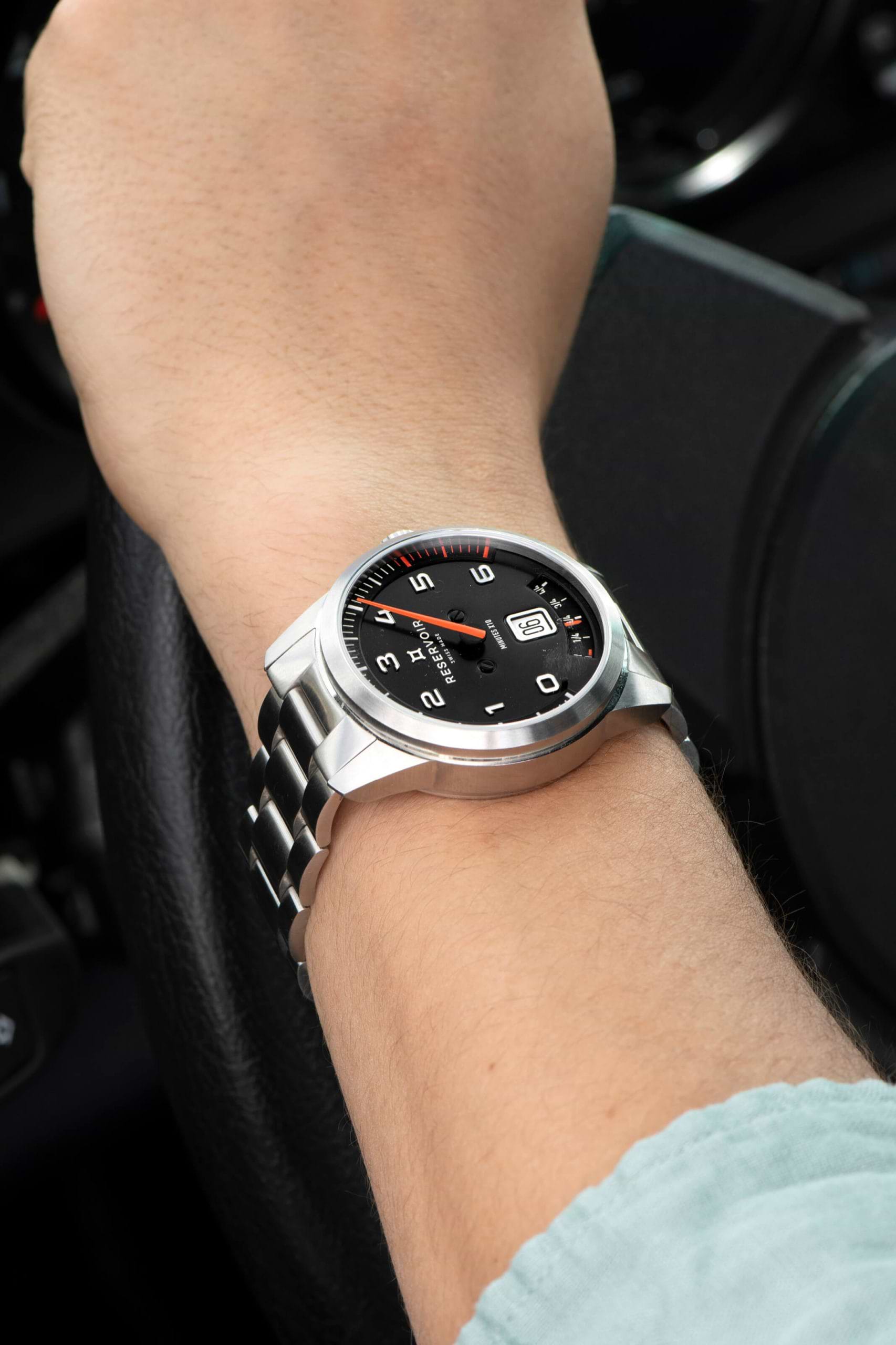 Media editorial of luxury RESERVOIR watch featuring light tan, very dark grey, and dark brown shades.