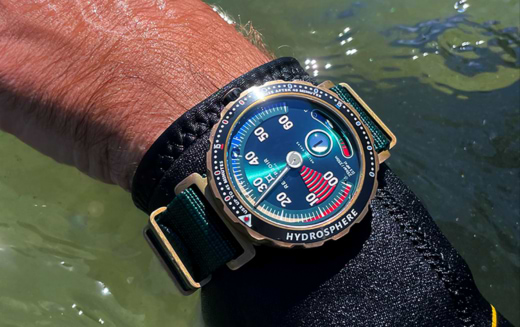 Close-up of a wrist wearing a blue-dial "Hydrosphere" diving watch near water, with a durable strap.