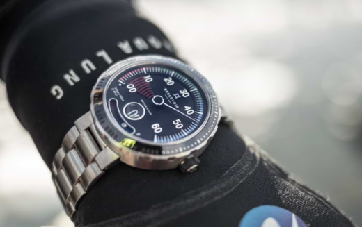 Diving watch on a wrist wearing an "AQUA LUNG" wetsuit, displaying clear numerals for easy reading.