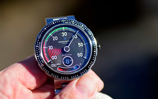 Metallic watch showing reserve power with engraved bezel indicating second intervals.