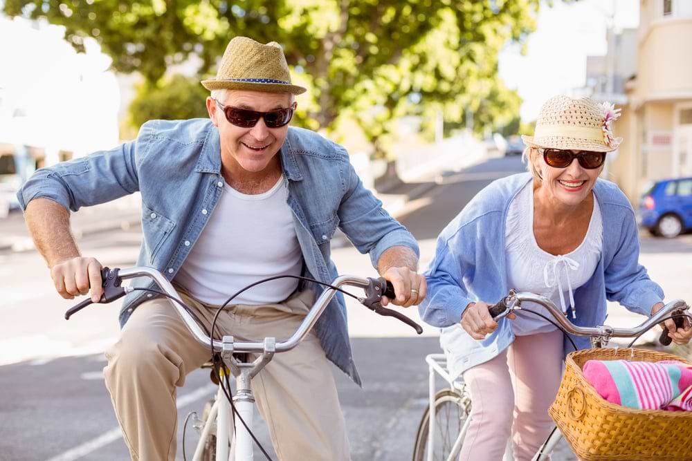 Happy mature couple going for a bike ride in the city on a sunny day