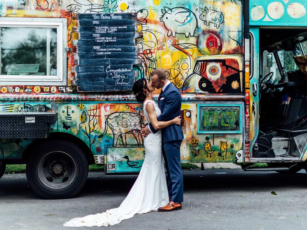 Bride and groom kissing in front of food truck