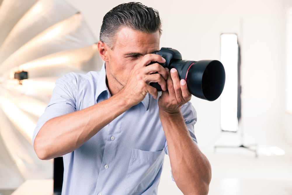 Handsome photographer making photo on camera in studio