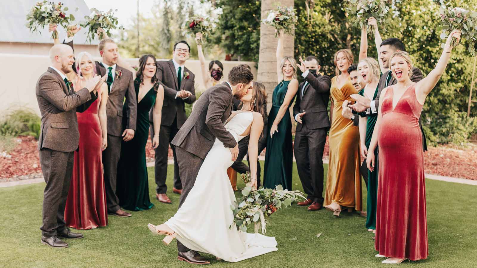 Photo of A bride poses with her bridesmaids in coordinated outfits