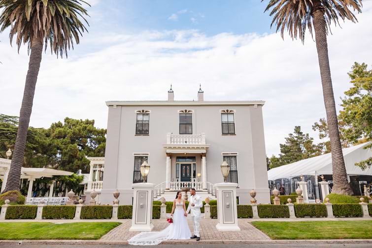 Bride and groom posing in front of historic mansion wedding venue - Jefferson Street Mansion by Wedgewood Weddings