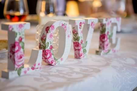 A white “love” sign with pink flowers on a table