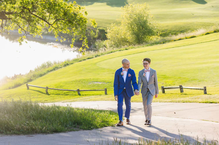 Groom and groom walking up pathway on green golf course - Boulder Ridge by Wedgewood Weddings