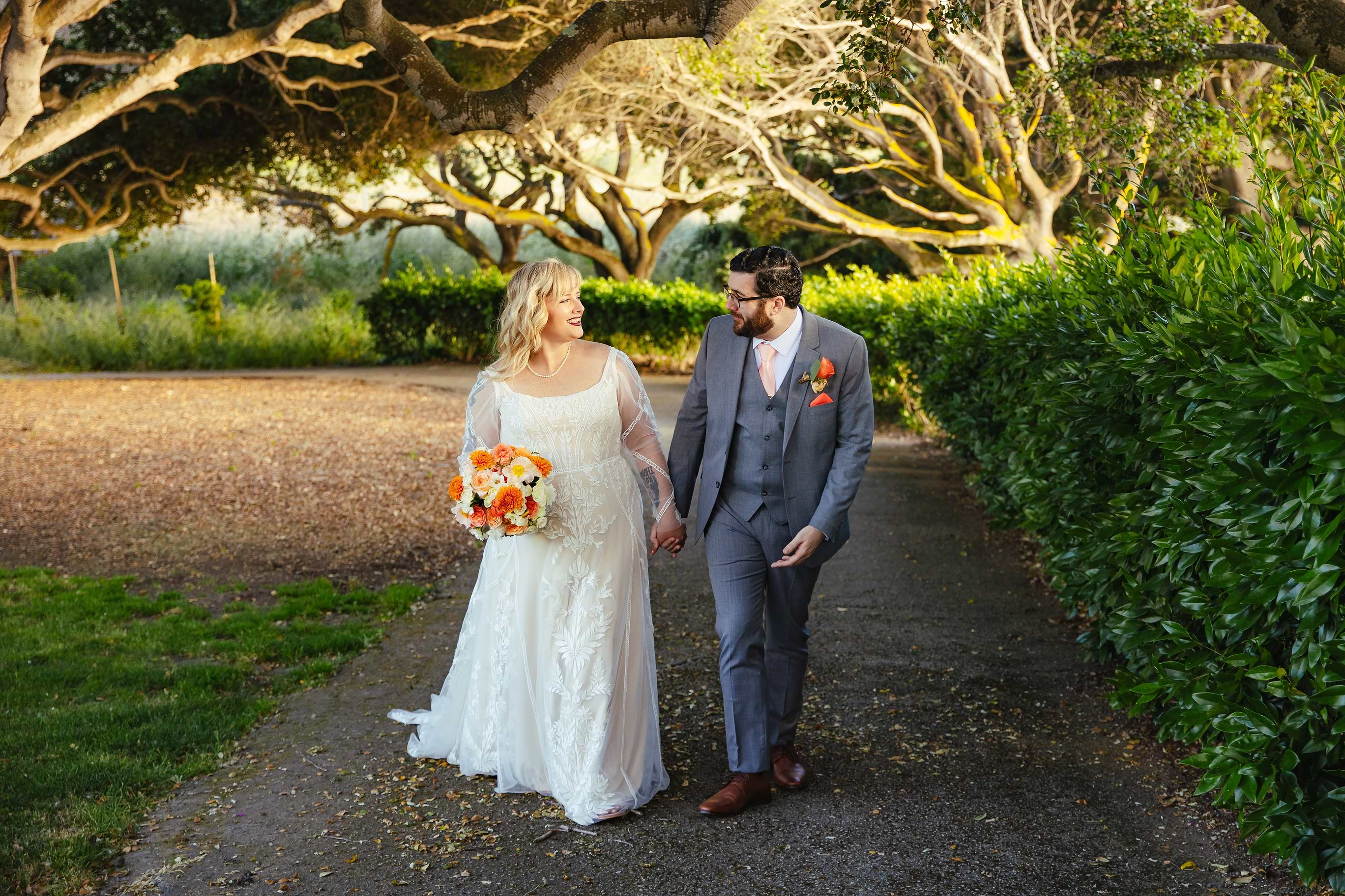 Newlyweds strolling through trees at Carmel Fields by Wedgewood Weddings