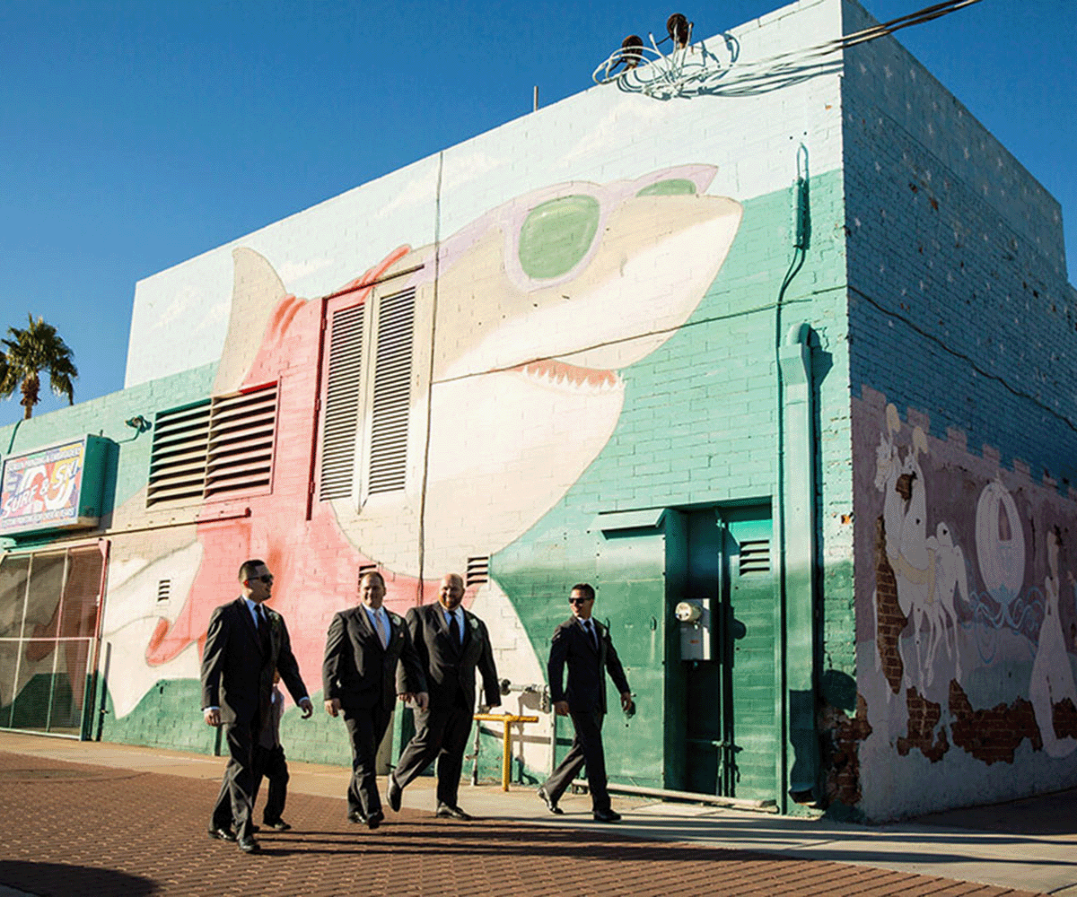 Groomsmen walking in front of mural at Tre Bella in Mesa