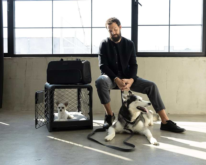 Image showcasing the collection : A man sitting with a dog next to a dog crate and carrier 