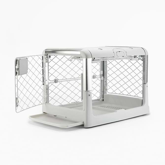  A white dog crate its tray partially pulled out and open doors 