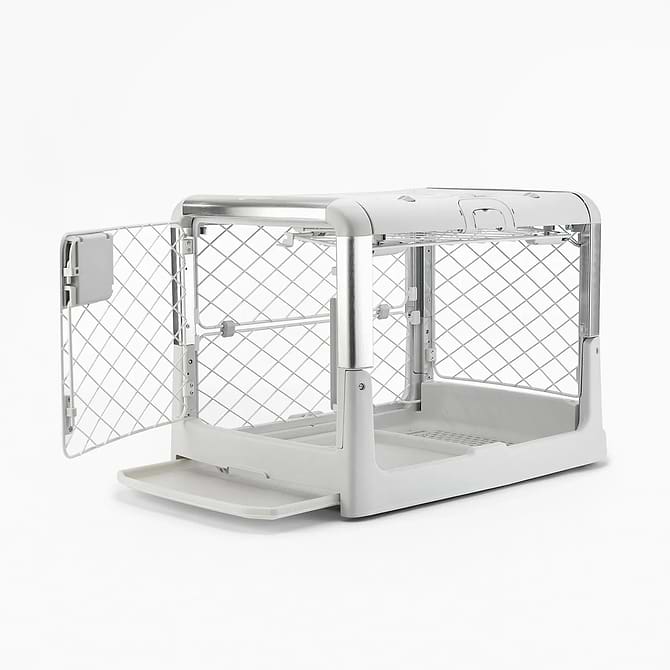 A white dog crate its tray partially pulled out and open doors