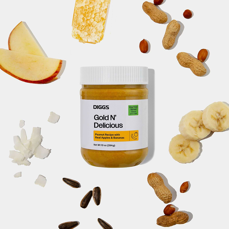 Gold n' Delicious Peanut Butter Treat Spread on white background beside its ingredients (apple, banana, peanuts, etc)