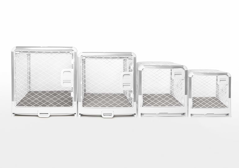  Four white dog crates of varying sizes sitting next to each other 