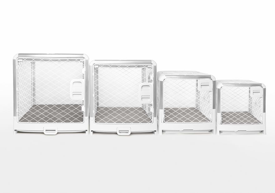 Four white dog crates of varying sizes sitting next to each other