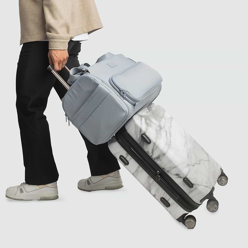 A person pulling a piece of luggage with a Passenger bag attached