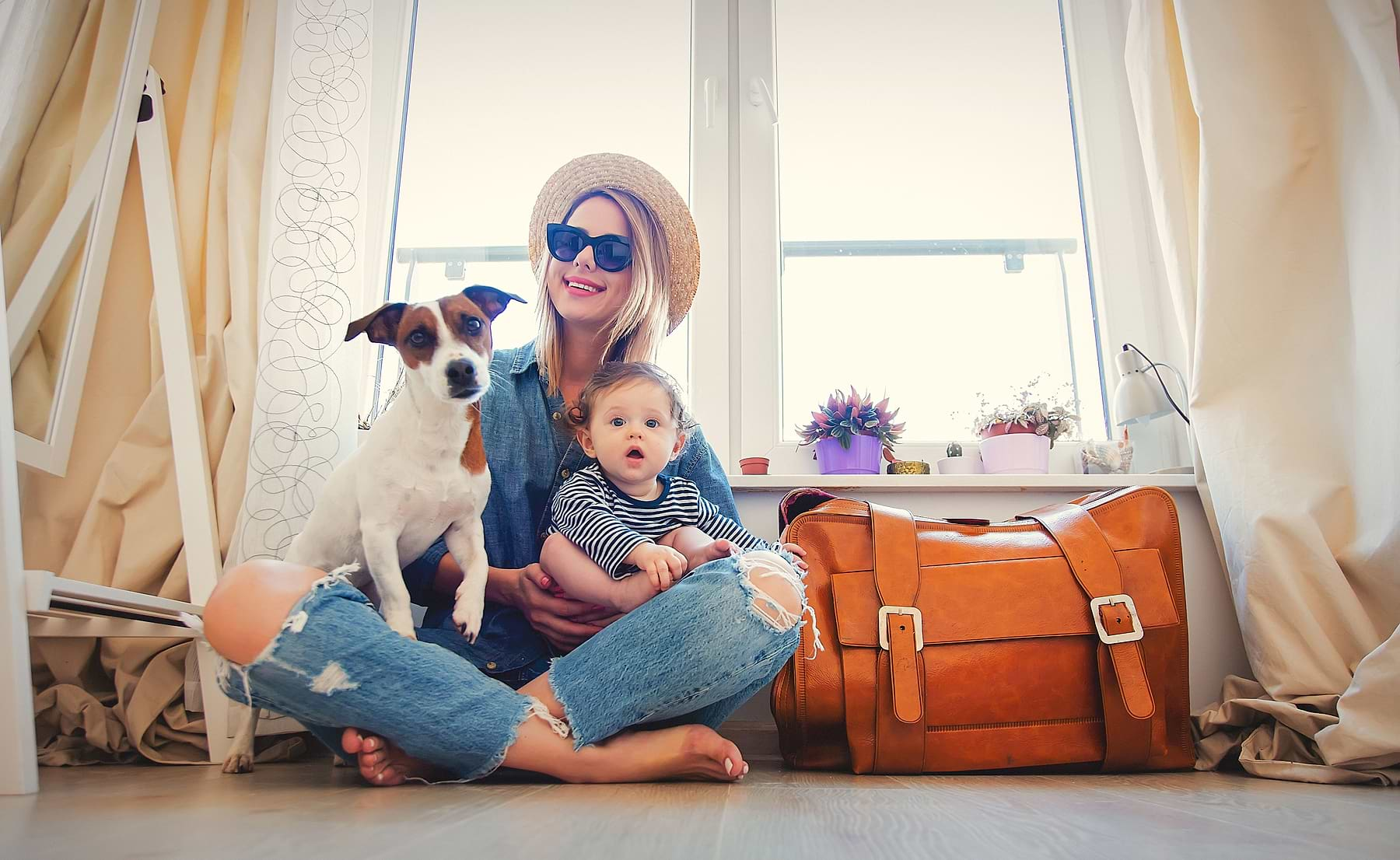  A photo of a dog, a kid, and the owner sitting on the floor smiling to the camera. 