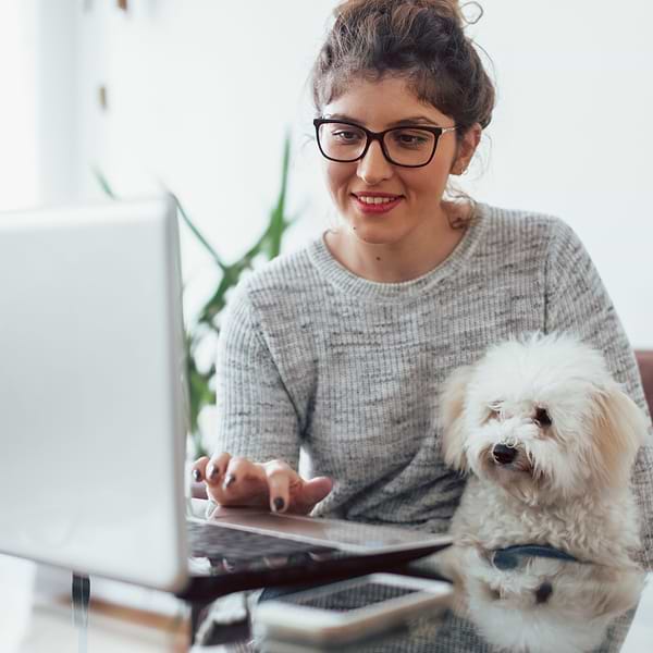  a woman sitting at a table with a dog on her lap 