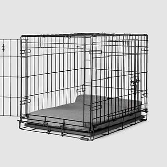  A dog crate with a Bolstr bed inside of it 