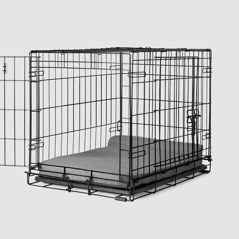 A dog crate with a Bolstr bed inside of it