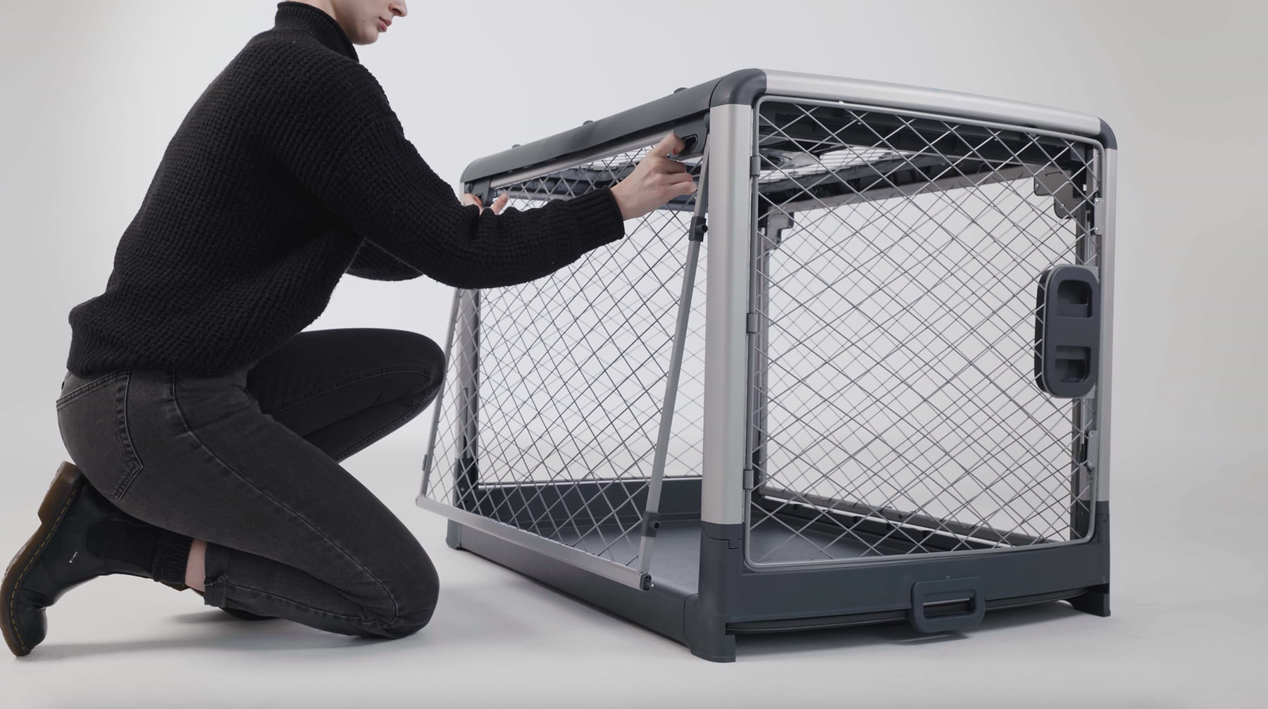  A model wearing a black sweater and black pants showing how to disassemble a crate. 