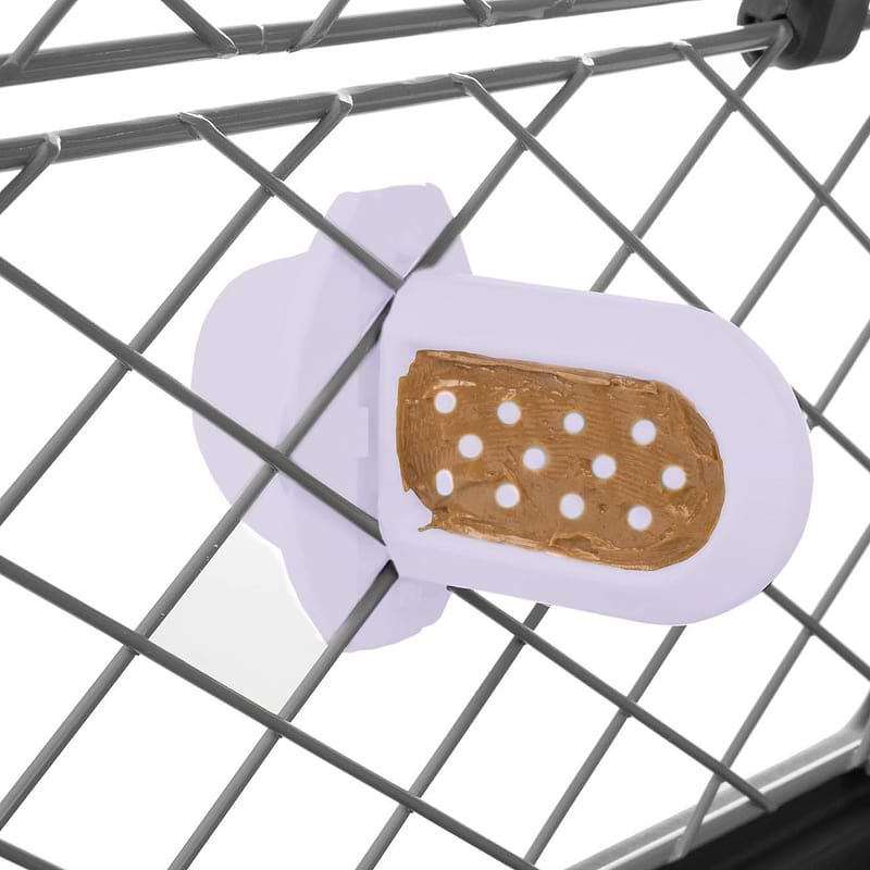 Groov Crate Training Aid in Lilac, attached to the mesh of a dog crate, with peanut butter spread on the grooves