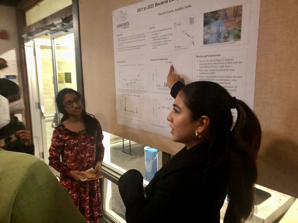 Anshika Sinha of Fairfield Warde High, left, and Danielle Garcia of Norwalk High School, discuss their research regarding bacteria counts in Stony Brook. / Photo by Thane Grauel