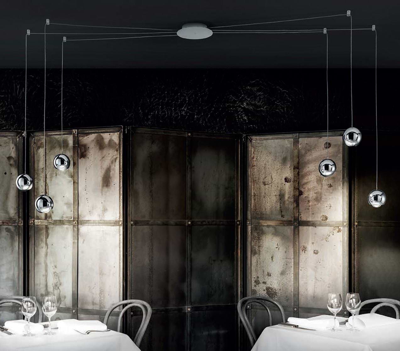 Industrieel maar sjiek restaurant met stijlvolle moderne projectverlichting boven de eettafels. Hanglampen met drie mooie bollen.