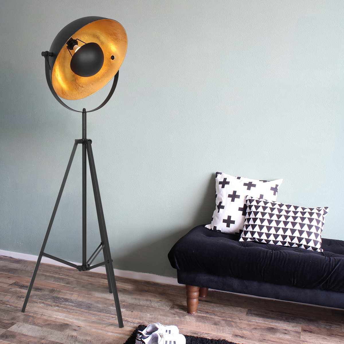 Zwarte vloerlamp met gouden binnenzijde. Deze grote, driepotige lamp zorgt voor zowel een moderne als industriële sfeer.